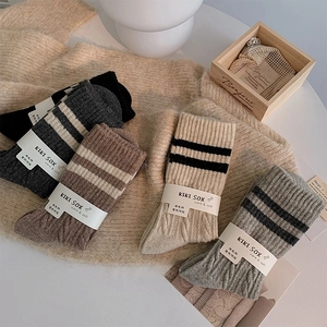 Close-up of thick cable knit wool socks in neutral tones with minimalist packaging