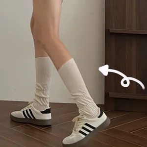 Detailed macro view of cream ribbed calf-high socks paired with retro striped sneakers