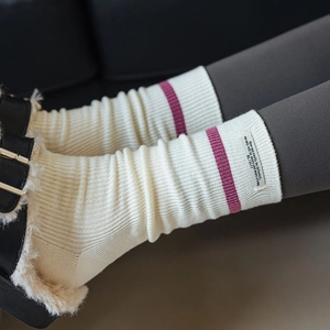 Dettaglio di calze in cashmere a coste color crema con strisce viola ed etichetta