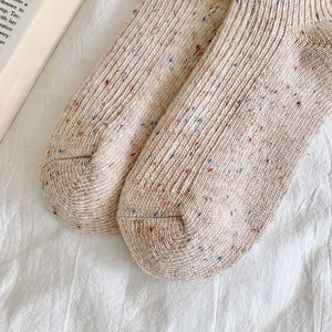 Close-up of oatmeal knit wool socks showing ribbed texture and colorful flecked yarn details