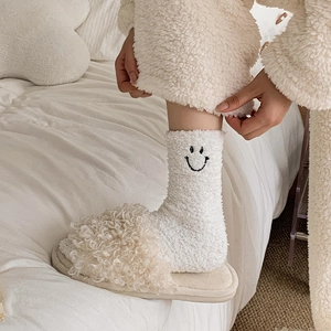 Close-up of cozy white coral fleece socks featuring a black smile embroidery detail