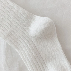 Detailed close-up of rib-knit white socks showing fine stitching and reinforced heel texture