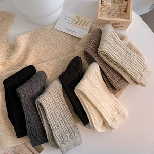 Detailed texture of thick cable knit crew socks in various warm vintage earth tones