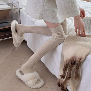 Close-up of beige ribbed knit over-the-knee socks with soft texture for winter warmth
