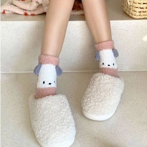 Détail de chaussettes en molleton corail à oreilles 3D et pantoufles en peluche blanche