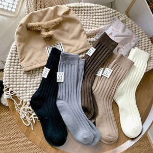 Close-up of ribbed knit socks with fabric tags and a matching beanie in earthy tones