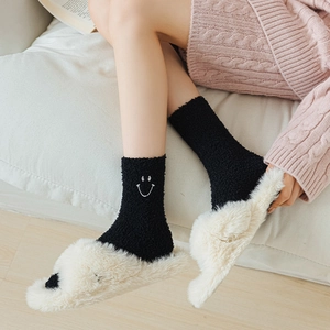 Close-up of cozy coral fleece socks with embroidered smile and white faux fur slippers