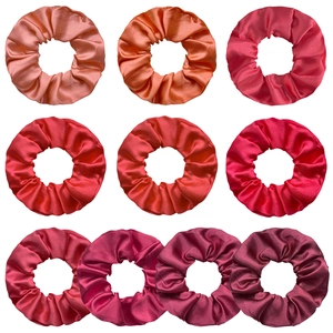 Detail view of 10 satin scrunchies in a gradient of pink, red and burgundy silk fabric