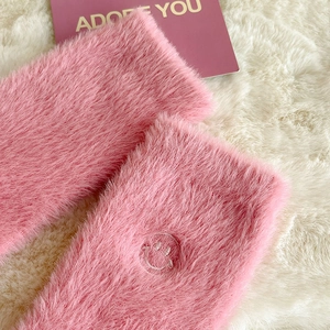 Dettaglio dei calzini di peluche rosa con ricamo a forma di faccina sorridente