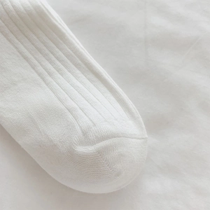 Close-up of white ribbed knit socks showing detailed stitching and soft cotton texture