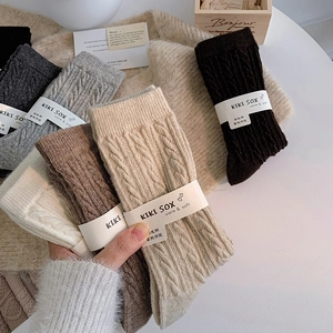 Macro shot of assorted cable knit wool socks featuring warm textured patterns in neutral colors