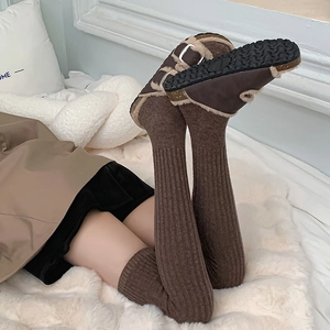 Detail of coffee brown ribbed over-knee socks paired with warm faux fur lined mules