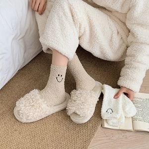 Close-up of cozy coral fleece socks with embroidered smiley face and plush slippers