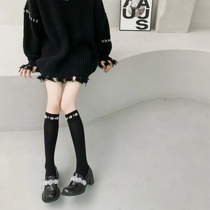Detail of black calf socks with pearl embellishments and platform floral loafers