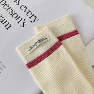 Dettaglio del polsino in maglia a coste crema con riga bordeaux ed etichetta in tessuto