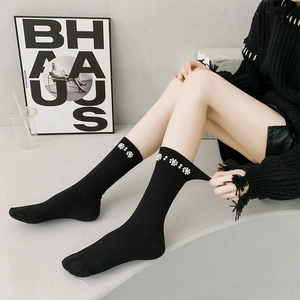 Detailed macro view of black ribbed calf socks with exquisite white pearl floral decorations