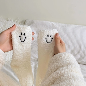 Detailed view of white coral fleece sock featuring a cute black embroidered smile face