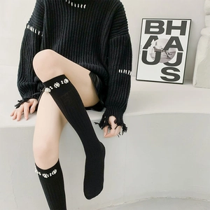 Detail of black calf socks featuring delicate white pearl trim and premium knit texture