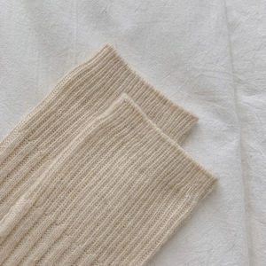 Close-up of beige wool knitted over-knee socks showing soft ribbed texture and thick weave