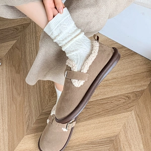 Detail of khaki suede loafers with plush faux fur lining on a warm wooden floor