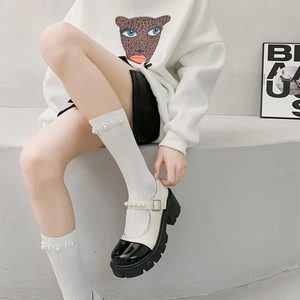 Close-up of black and white Mary Jane shoes with pearl straps and matching socks