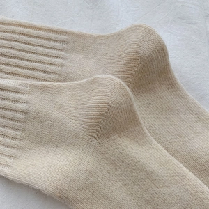 Close-up of cream white wool blend over-the-knee socks with vertical rib-knit texture