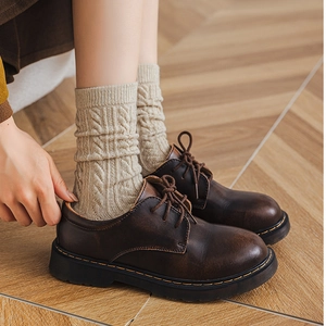 Close-up of beige cable knit socks styled with dark brown vintage leather oxford shoes