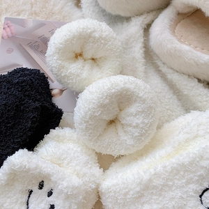 Detail shot of fluffy coral fleece socks with cute smiley embroidery and soft texture