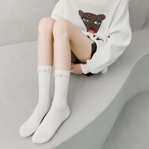 Detail view of white ribbed calf socks featuring hand-stitched decorative pearls