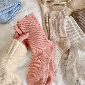 Close-up of thick speckled wool socks with ribbed texture in multiple colors