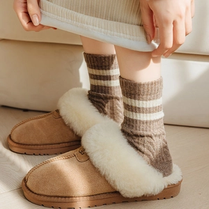 Brown suede snow slippers with thick white fleece lining and cozy striped wool socks