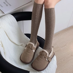 Close-up of warm brown suede mule slippers with plush fleece lining and knitted socks