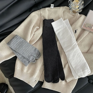Close-up of three pairs of ribbed split-toe socks in grey stripes, black, and white colors