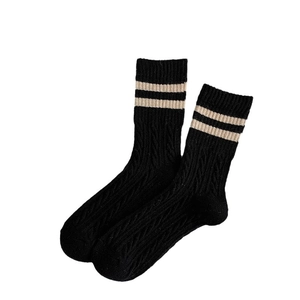 Thick wool socks in black with cable knit texture and white stripes in preppy style