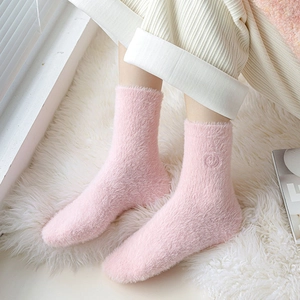 Dettaglio di calze di peluche rosa con un delicato motivo a forma di faccina ricamata