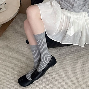 Detail of grey and white vertical striped crew socks with ribbed cuffs on model feet