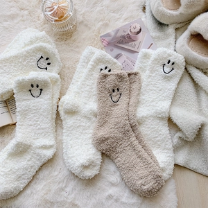 Detail of coral fleece winter socks with cute smiley embroidery in home setting