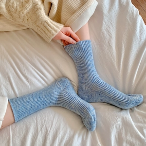 Close-up of thick light blue knit wool socks with vertical ribbed texture and mottled finish