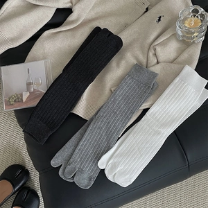 Close-up of ribbed Tabi socks in black grey and white featuring split-toe detail