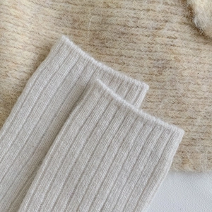 Close-up of thick ribbed knit wool socks in cream color with soft textile texture