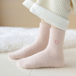 Dettaglio di calze in pile corallo rosa con ricamo a forma di faccina per l'inverno