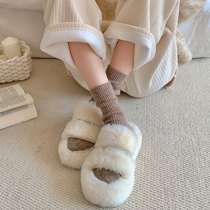 Close-up of plush faux fur slippers with thick soles and warm knitted crew socks
