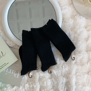 Three pairs of black ribbed knit socks displayed on a white plush carpet in a home setting