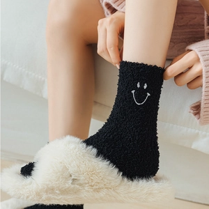 Close-up of black fuzzy coral fleece socks with cute white embroidered smiley face
