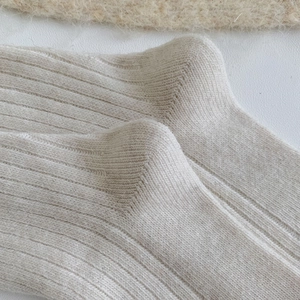 Close-up of ribbed knit texture on thick beige wool socks with soft mohair finish