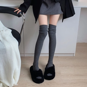 Detail of dark grey rib-knit over-the-knee wool socks showing thick vertical texture