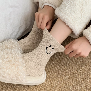 Close-up of oatmeal coral fleece socks with smiley embroidery and plush texture