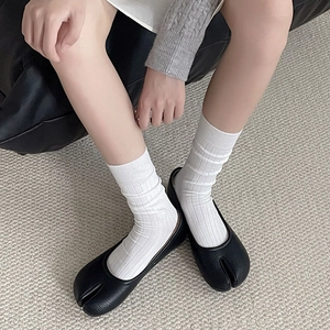 Detail of black leather Tabi split-toe shoes worn with white ribbed cotton mid-tube socks