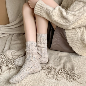 Detailed knit texture of oatmeal wool socks with colorful speckles and ribbed cuffs