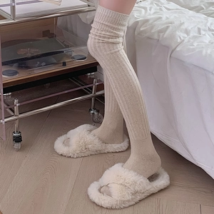 Detailed knit texture of beige over-the-knee wool socks with vertical striped patterns